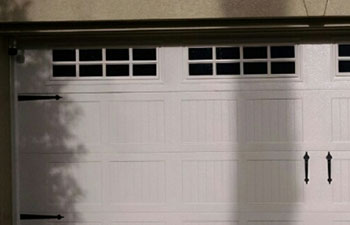A residential house double garage with white garage door with windows