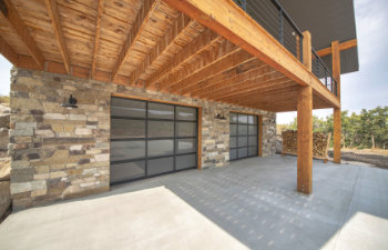 custom home garage exterior with stone walls and double glass garage doors